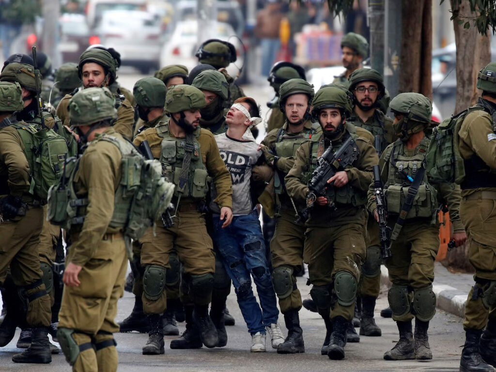 Palestinian boy being detained by several men of Israeli forces